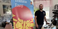 Kenneth står vid sitt skrivbord med Trollhättan Energi-backdropp bakom