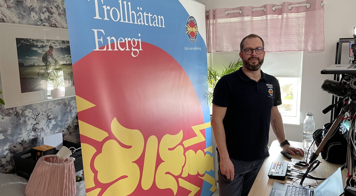 Kenneth står vid sitt skrivbord med Trollhättan Energi-backdropp bakom
