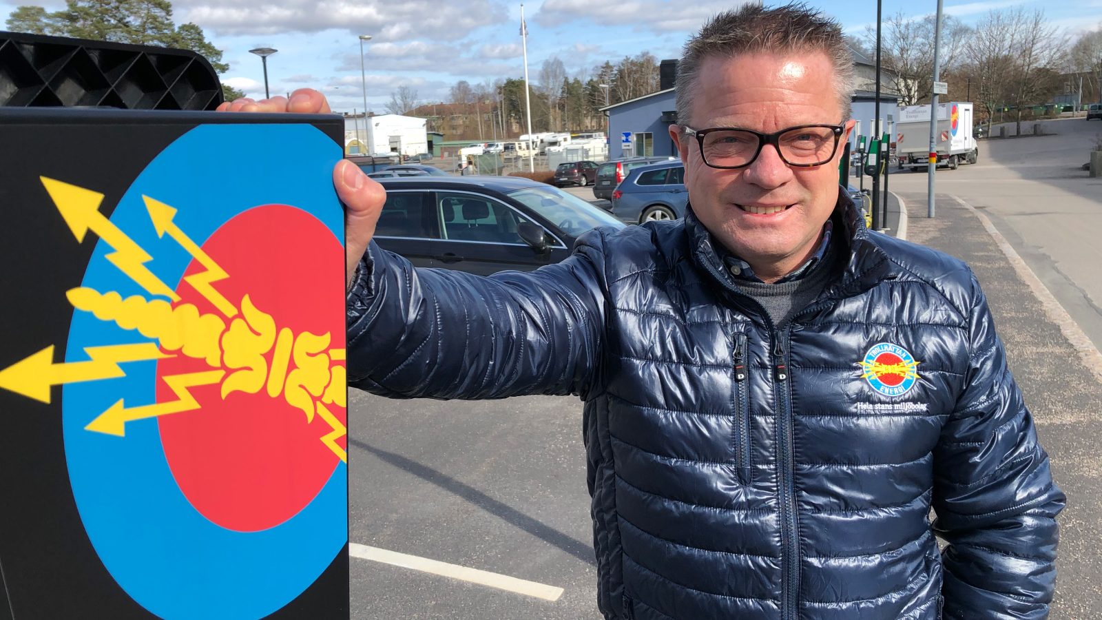 Man står vid laddstolpe med Trollhättan Energilogga på