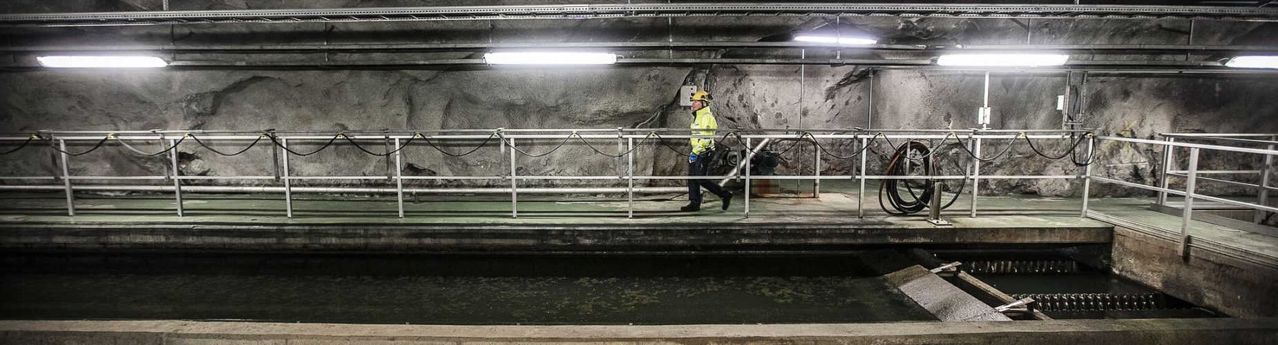 Tjej går i vid avloppsvatten i bergrum