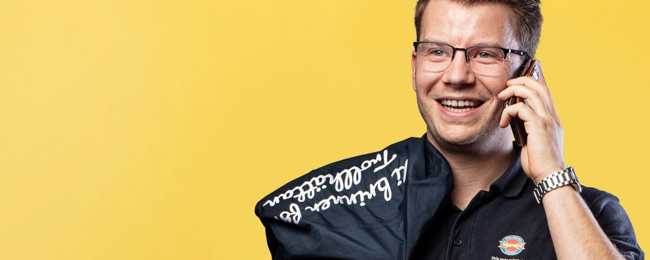 Kille ler och pratar i telefon. Håller jackan slängd över axeln.
