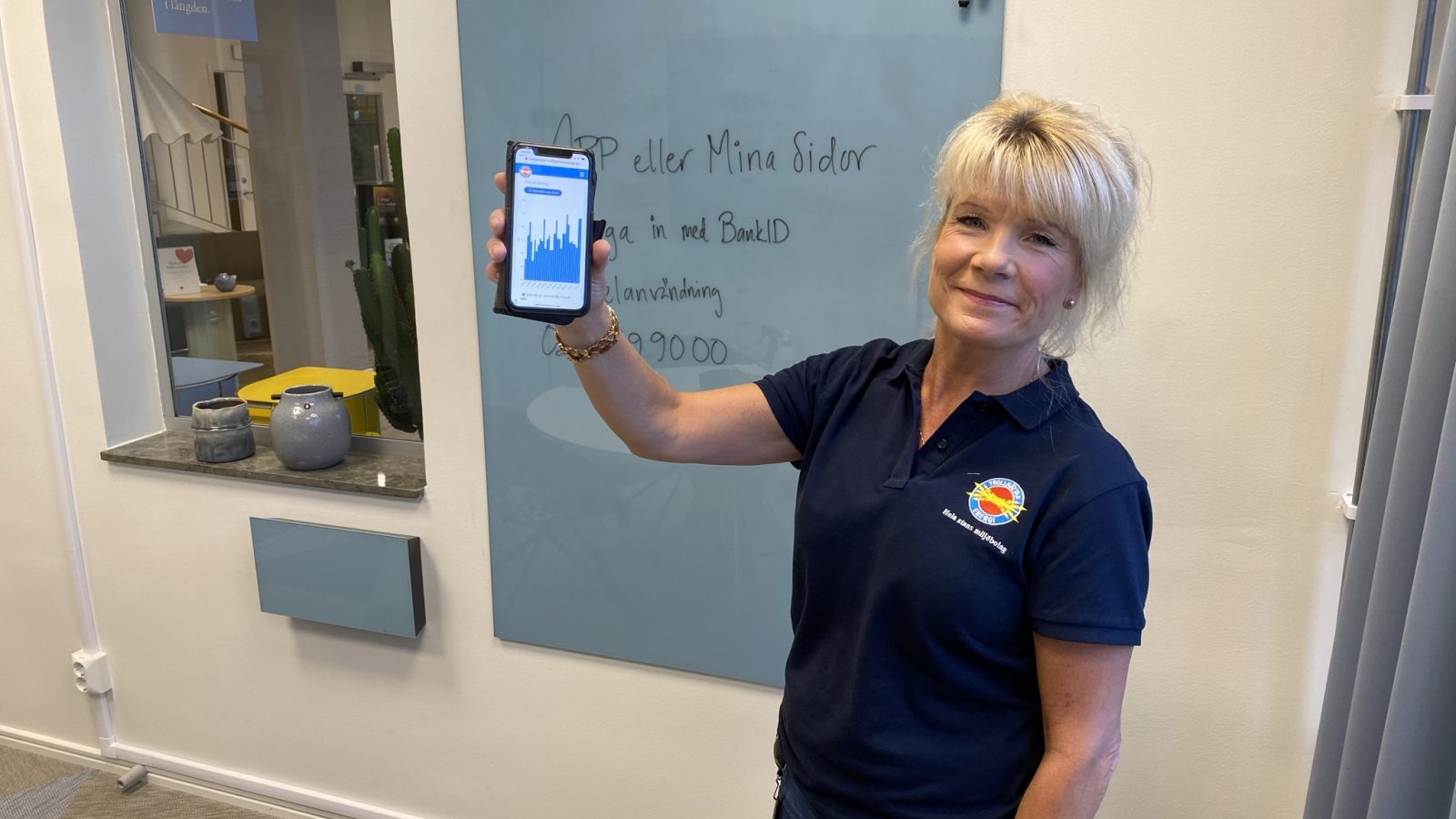 Kvinna visar en mobiltelefon mot kameran