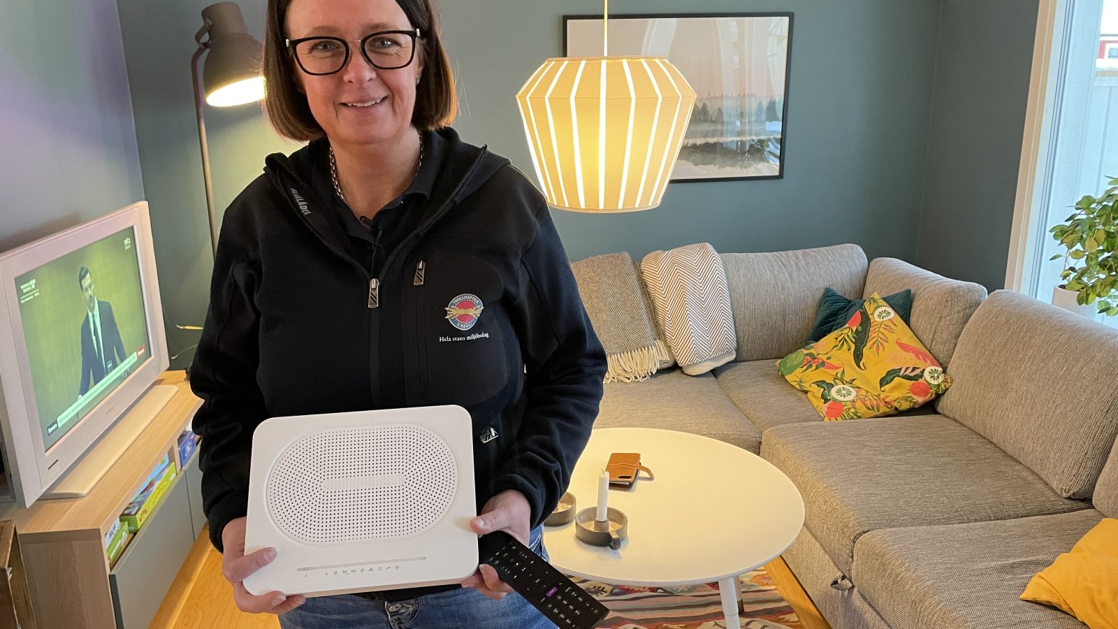 Tjej håller i en router och tittar in i kameran