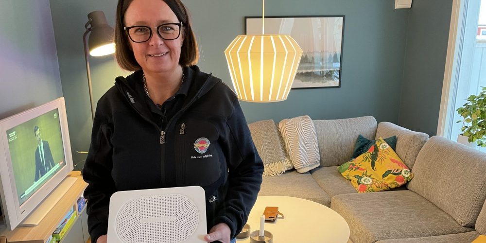 Tjej håller i en router och tittar in i kameran