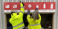 Två personer monterar upp en skylt