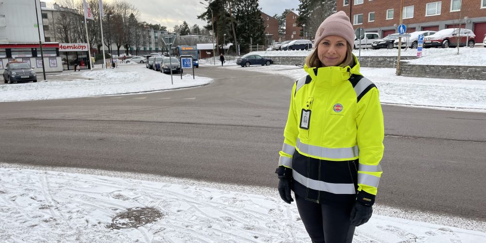 Tjej står ute i snön med varseljacka och mössa, vid en väg, tittar in i kameran.