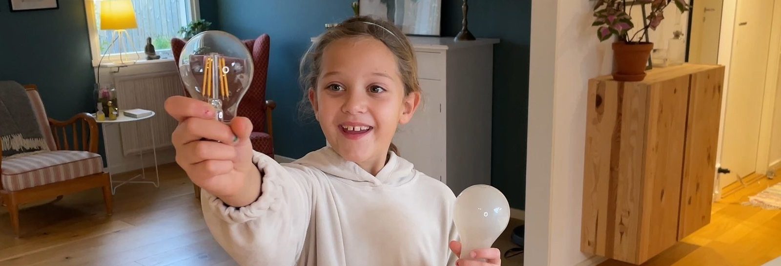 Tjej håller upp en LED-lampa mot kameran och ser glad ut