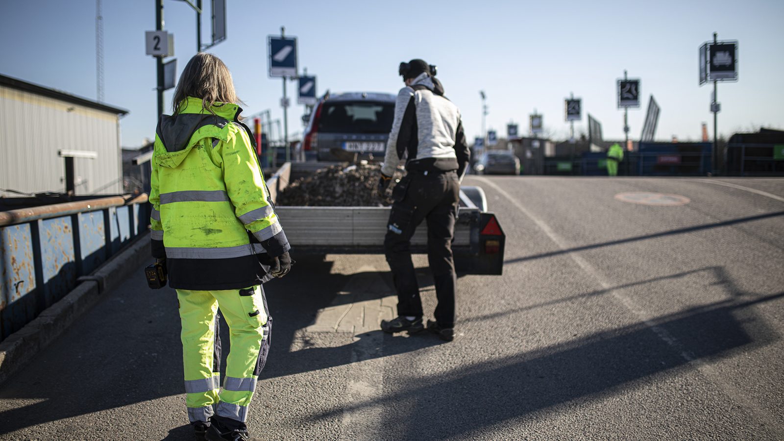 Personal på återvinningscentralen hjälper kund som lastar av sin kärra