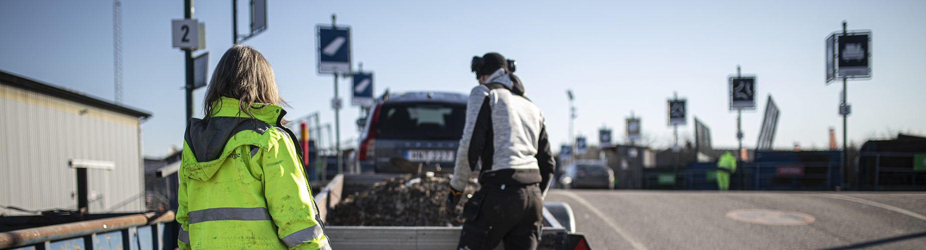 Personal på återvinningscentralen hjälper kund som lastar av sin kärra